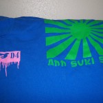 Blue t-shirt featuring a pink dripping "D4" symbol on the left and a green sunburst with "Ahh Suki Suki" on the right—a bold choice for fans of unique printed tshirts and custom t shirts. Rain City West