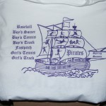 White sweatshirt with a purple graphic of a sailing ship labeled "Pirates," listing school sports teams and "spring season" on a banner. Rain City West
