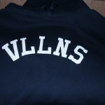 A navy blue sweatshirt with the letters "VLLNS" printed in white across the chest—perfect for adding comfort and style to your daily routine or casual workdays. Rain City West