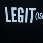 A black shirt with the word "LEGIT(ISH)" printed in large white letters—perfect for adding some humor to your daily routine or work wardrobe. Rain City West
