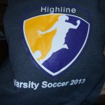 A sweatshirt from Team Highline Gear featuring the Highline Varsity Soccer 2013 logo, with a stylized soccer player kicking a ball inside a yellow and purple shield. Rain City West