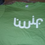 A green TWIF T-shirt with stylized white Arabic text printed across the front—perfect for anyone who believes the World Is Fun. Rain City West