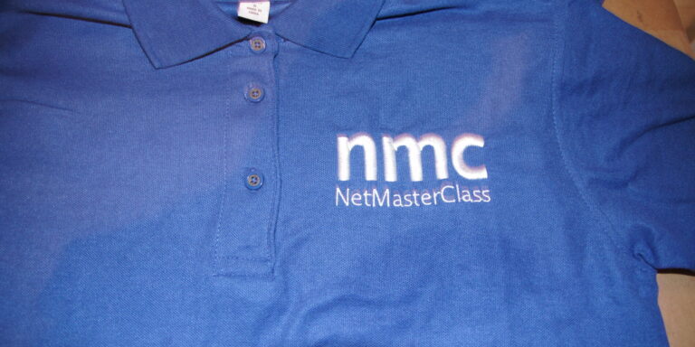 Blue collared shirt with "nmc NetMasterClass" embroidered in white on the left chest, featuring quality GGC Embroidery for a professional finish. Rain City West