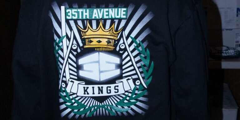 Person wearing a black hoodie with a large graphic on the back that reads "35th Avenue Kings," perfect for skateboarding, featuring a crown, laurel leaves, and bold geometric shapes. Essential skate gear from 35th Ave. Rain City West